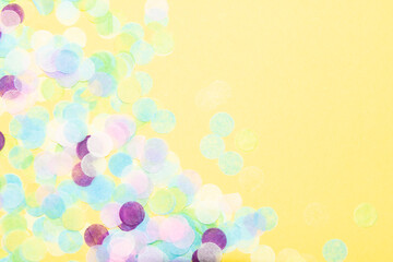 Blue, green, purple, pink and yellow paper confetti on a vibrant yellow background