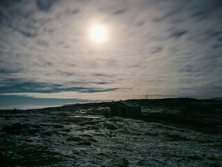 Moonlight over a old dilapidated house on a rocky shore. Night mystical scenery. Winter Teriberka.