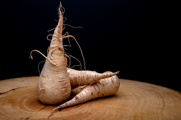 A trio of parsnips, set upon a wooden board, showing them to be a root vegetable.