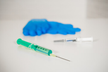 Syringes with vaccine and blue medical gloves in the background: Curing the Covid pandemic by mass...