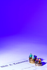 Conceptual image of miniature a figure couples sat on coins at the side of a last will and...