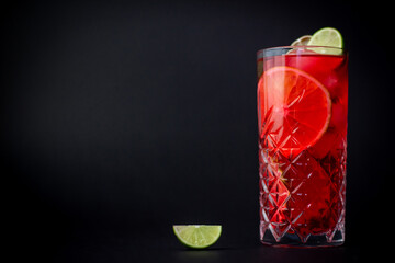 Fresh red cocktail with oranges and lime on black background