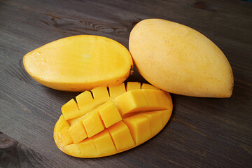 Fresh Ripe Mango Cut in Half and Crosswise Cut with a Whole Fruit on Black Wooden Background