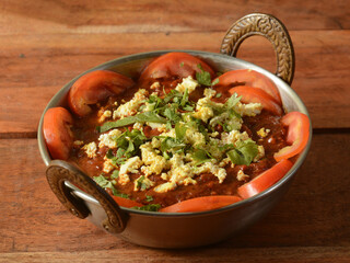 kadai paneer is a famous indian dish, served over a rustic wooden background, selective focus