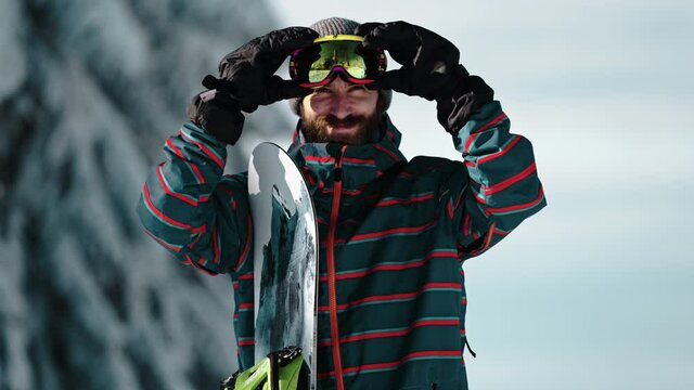 Close up of snowboarder puts on his snowboard goggles glasses shot in 4k super slow motion