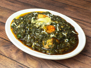 Palak Paneer Curry made up of spinach and cottage cheese, helathy indian traditional dish, served over a rustic wooden background, selective focus