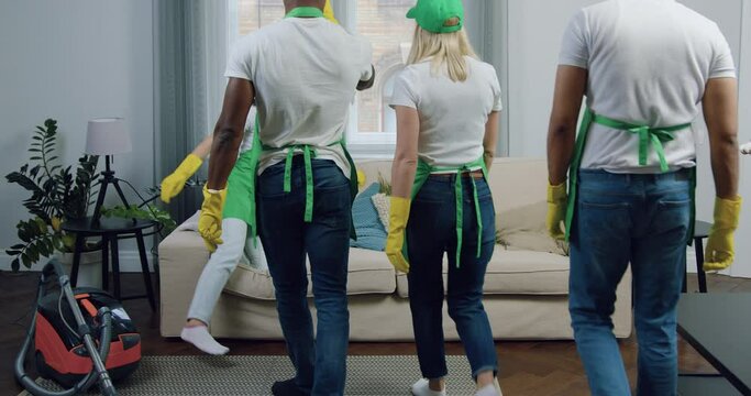 Good-looking happy satisfied and tired multiracial team of cleaners relaxing on comfortable sofa in contemporary apartment after cleaning up ,close up