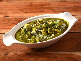 Palak Paneer Curry made up of spinach and cottage cheese, helathy indian traditional dish, served over a rustic wooden background, selective focus
