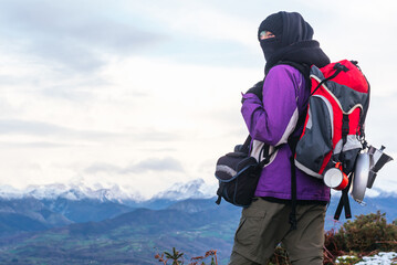 hiker taking a breather on his ascent to the mountain in winter. Bring a backpack and warm clothes. it's winter and there's snow