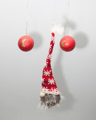 muñeco barbudo con gorro rojo y blanco de papa noel suspendido en el aire junto con 2 bolas rojas de decoración navideña