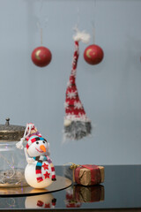 adornos de navidad rojos colgando en el  aire y muñeco de nieve sonriente en primer plano