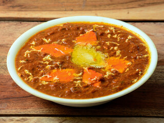 Paneer Butter Masala or Cheese Cottage Curry, served over a rustic wooden background, selective focus