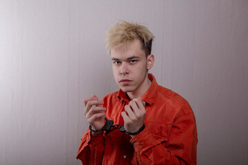 a teenager in handcuffs on a gray background. juvenile delinquent, criminal liability of minors....