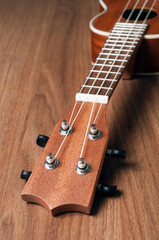 Mahogany soprano ukulele resting on wooden table, vertical orientation