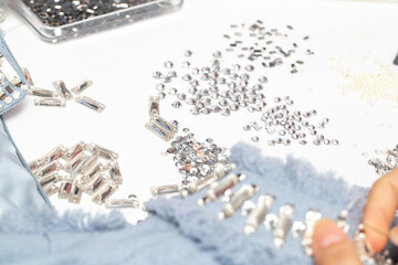 Embroidery process close up, tailor embellished blue dress with crystals