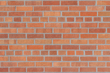 Fototapeta premium Full frame texture background of a grungy vintage brick wall in common bond pattern, with bricks in varying shades of orange and red, having a subtle shimmering surface patina.