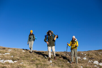 A group of friends is hiking at the top of the mountain. 