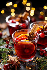 Christmas mulled red wine with citrus, spices and cranberries on a festive table close up view. Delicious Christmas hot drink