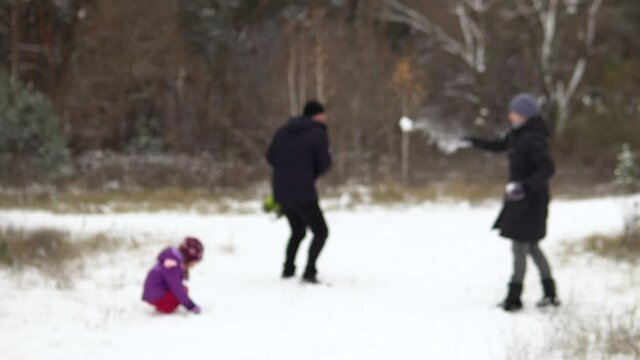 Blurred image of a family of four: mom, dad, son and daughter are playing snowballs in nature. Blurred background. Camping with the family.4k