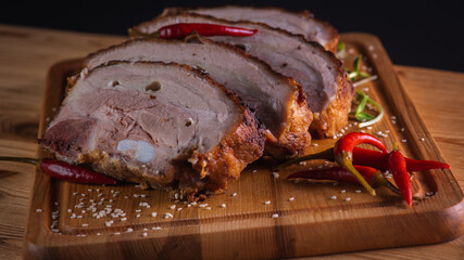 Grilled pork on a wooden cutting board on a brown background with hot red peppers. Delicious meat concept