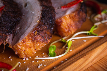 delicious, juicy and fragrant grilled pork, ribs on a wooden board on a dark background with hot red pepper and spices. Delicious meat concept
