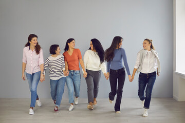 Obraz premium Group of happy confident women walking hand in hand, demonstrating mutual support and solidarity