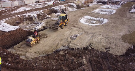 Obraz premium Aerial view of heavy machinery, tractor transporting land, construction preparation. The skating rink compacts the ground. Start of construction of the building flick.