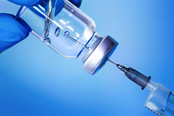 Vaccine in a bottle with a syringe on a blue background.The concept of medicine, healthcare and...