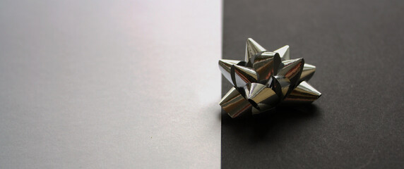 Single shiny silver gift bow on a black background. White backdrop. Template. Festive mock up.