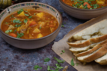 Vegan or vegetarian soup in ceramic bowls with herbed bread on gray table