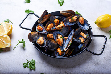 Paella repleta de mejillones cocidos al vapor en un fondo blanco con sus ingredientes.