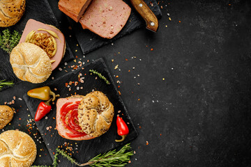 Flat lay composition of delicious hot dogs and sandwiches with different toppings on the dark background