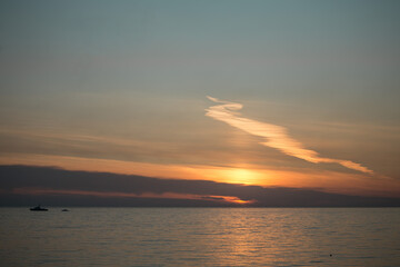 Sunset at sea with the sun hiding behind the clouds
