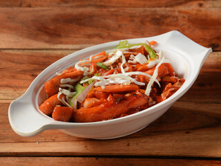 Paneer Manchurian is Indo Chinese cuisine dish, Paneer cubes tossed with tomatoes, onions, spring onions, sesame seeds and soy sauce. served over a rustic wooden background, selective focus