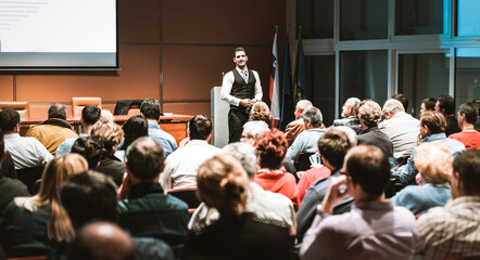 Speaker giving a talk in conference hall at business meeting event. Rear view of unrecognizable...