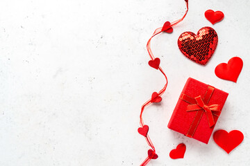 Valentine's day composition - red gift box and decorative, glitter hearts on white stone background. Flat lay, top view, copy space. Love concept.