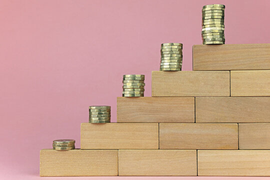 Piles of money on wooden tiers. Increasing amounts of debt concept.