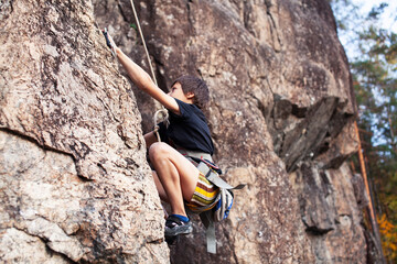 cute teen kid climbing on rock with insurance, lifestyle sport people concept