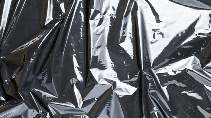 Plastic texture background. Wrap transparent dark cellophane. Cellophane black shiny film bag pattern. Creative crumpled background.