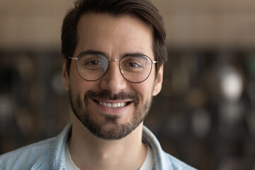 Close up portrait of smiling young Caucasian man in glasses look at camera show white healthy teeth. Happy millennial male in spectacles recommend good quality eyewear or optician services.