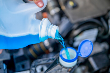 Pouring antifreeze. Filling a windshield washer tank with an antifreeze in winter cold weather.