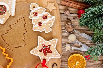 Process of cutting christmas gingerbread cookie dough on rustic wooden table with  cookie cutters.