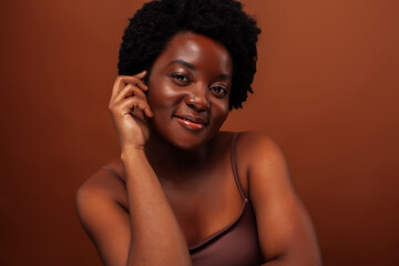 Fototapeta premium young pretty african model smiling happy on brown backround, lifestyle people concept