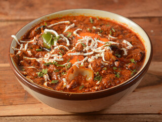 Paneer Tikka Masala is a famous indian dish, served over a rustic wooden background, selective focus