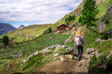 Naklejka na ściany i meble woman hiking to wooden house in the austrian alps