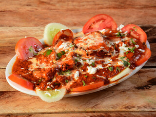 Paneer Tikka Masala is a famous indian dish, served over a rustic wooden background, selective focus