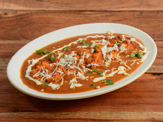 Paneer Tikka Masala is a famous indian dish, served over a rustic wooden background, selective focus