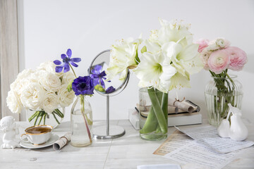 A bouquet of white roses in a round glass vase, a bouquet of white amaryllis, a cup of tea, a figurine on the table