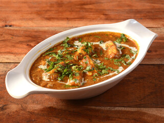 Paneer Masala or Cheese Cottage Curry, is a famous indian dish, served over a rustic wooden background, selective focus