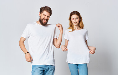 Portrait of a man and a woman in identical t-shirts teenager jeans light background